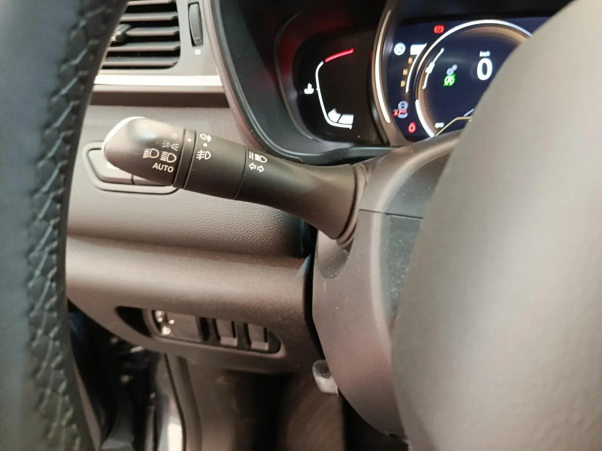 Gros plan sur la manette de commandes d'éclairage à gauche du volant dans le tableau de bord du Renault Kadjar Business gris foncé.