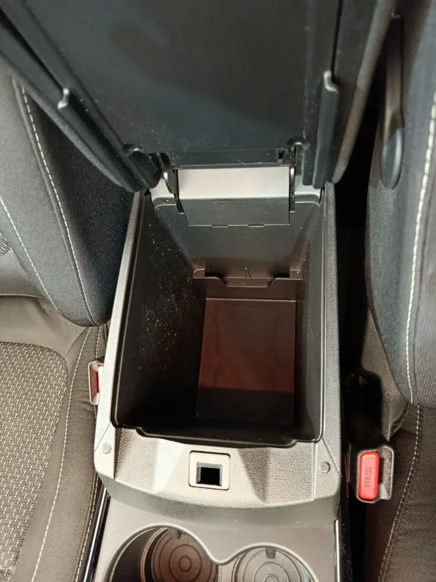 Vue plongeante sur le rangement central ouvert entre les sièges avant noirs du Renault Kadjar Business gris foncé.