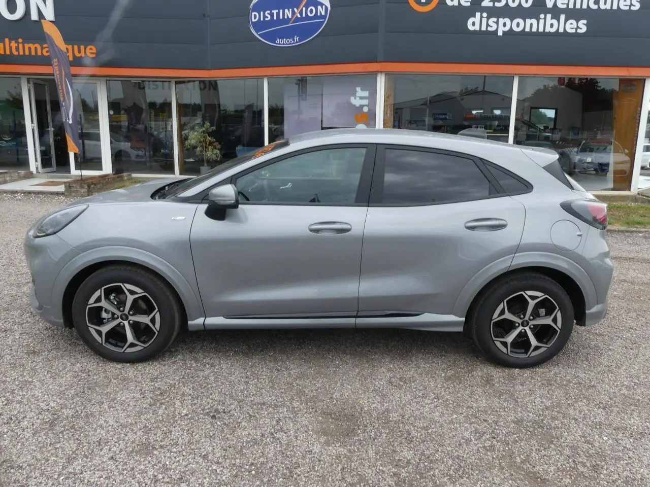 Vue de profil côté gauche du Ford Puma 2025 gris métallisé avec jantes alliage 17 pouces et vitres arrière surteintées.