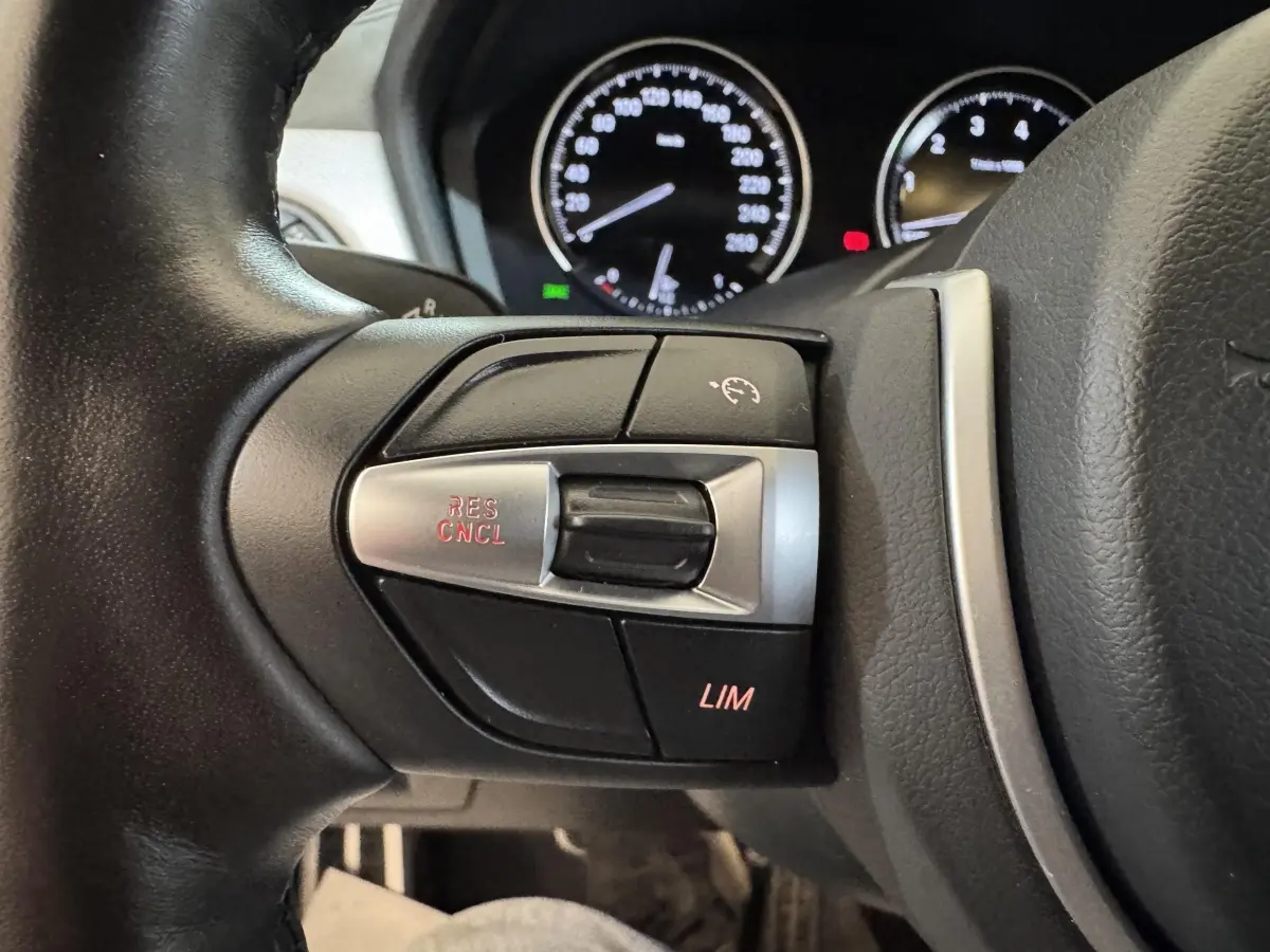 Gros plan sur les commandes du régulateur de vitesse au volant cuir d’une BMW X2 xDrive25e M Sport 2021.