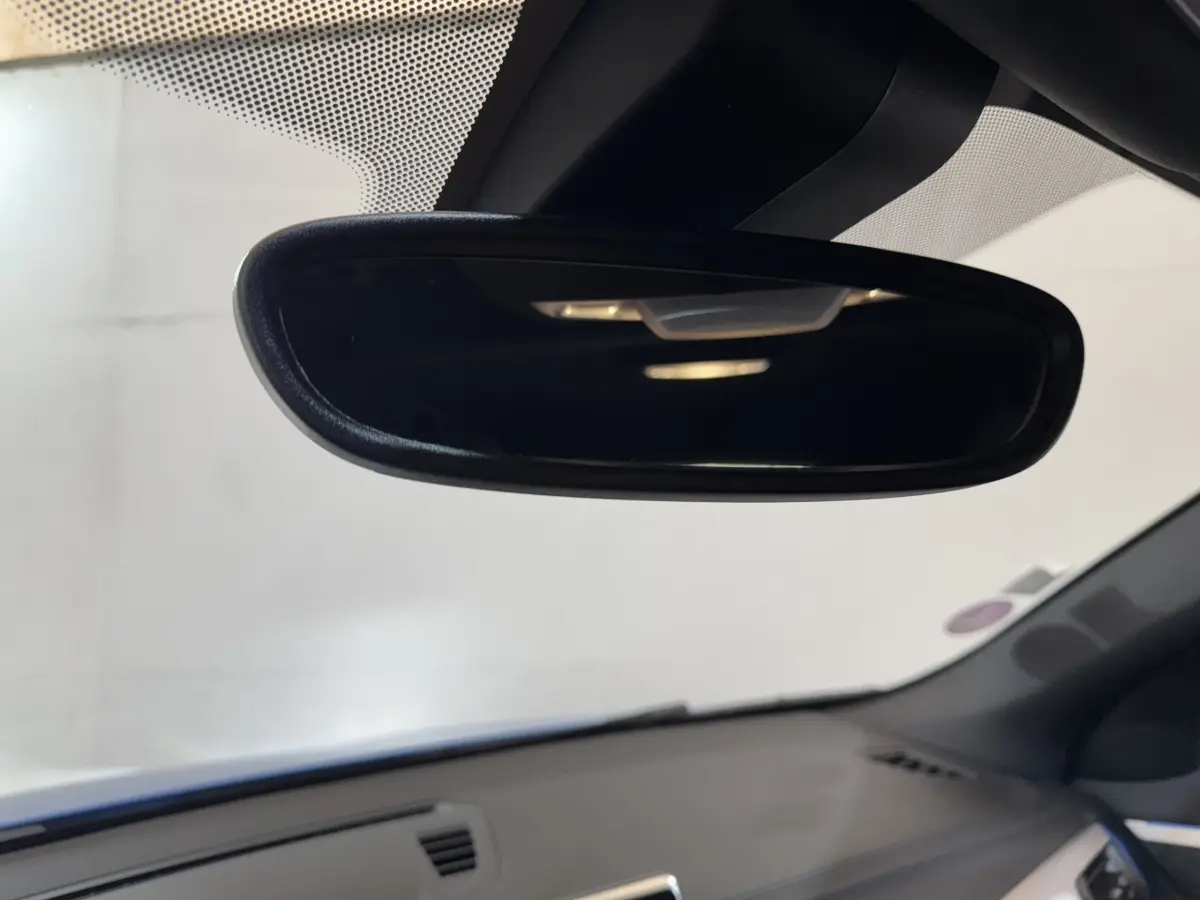 Vue intérieure centrée sur le rétroviseur intérieur d’une BMW X2 bleu, avec tableau de bord gris en arrière-plan.