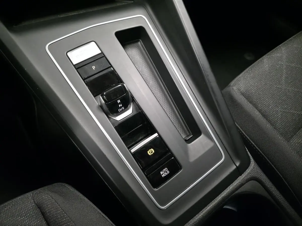 Gros plan sur la console centrale noire de la Volkswagen Golf VIII blanche, mettant en valeur le levier de vitesse automatique.