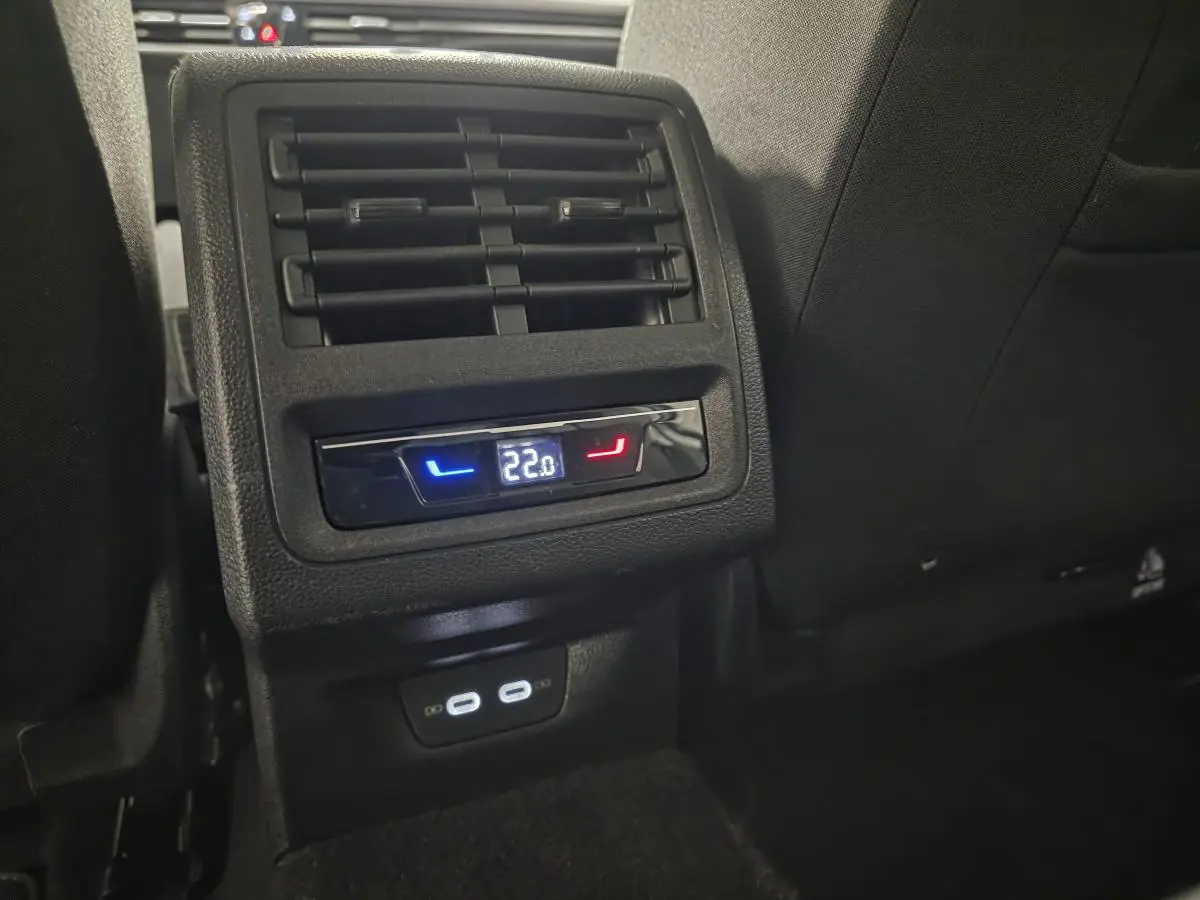 Détail de la console arrière noire avec ventilation et affichage digital de la climatisation à 22°C sur Volkswagen Golf VIII blanche.