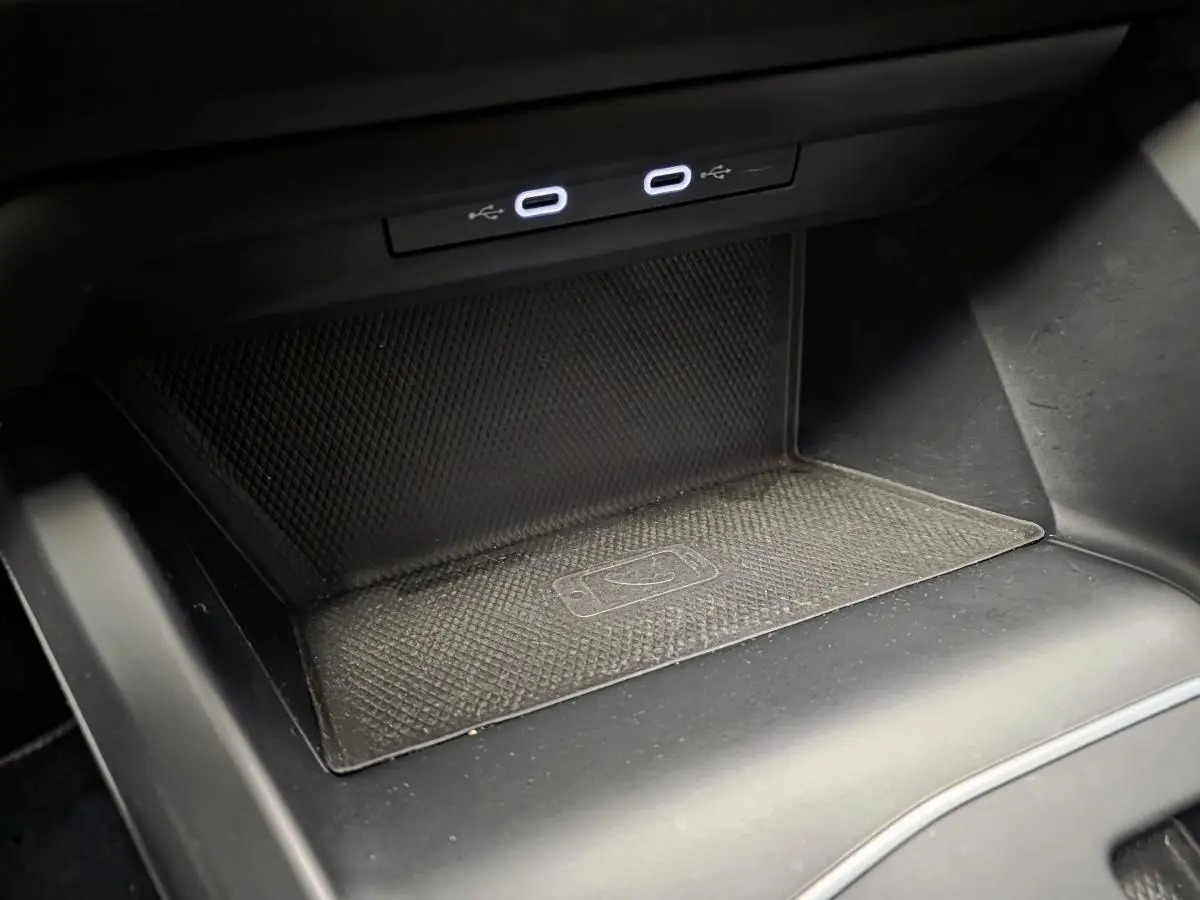 Gros plan sur la zone de recharge sans fil et deux ports USB-C éclairés dans la console centrale d'une Volkswagen Golf VIII blanche.