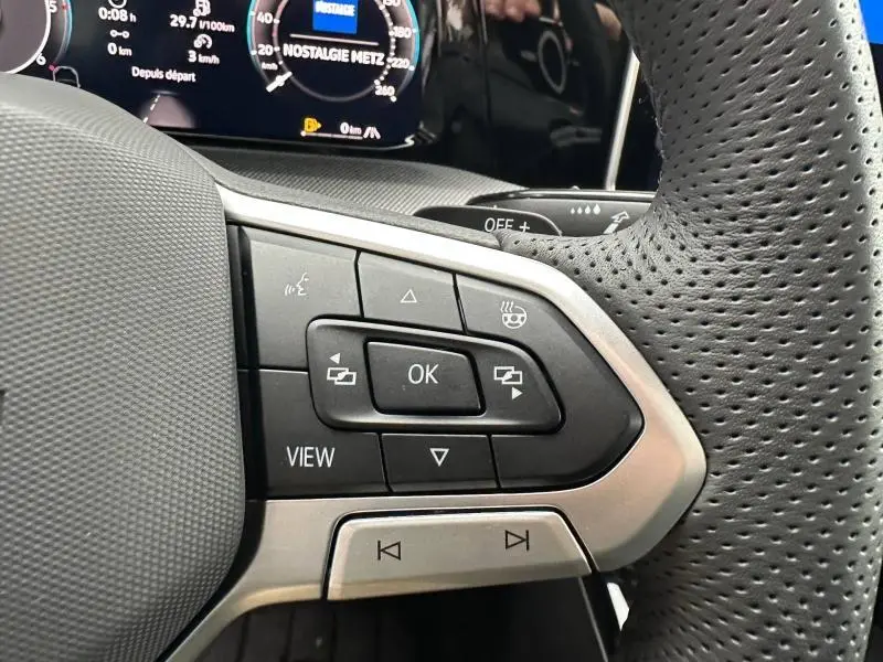 Gros plan sur les commandes multifonctions du volant cuir perforé côté gauche d'une Volkswagen Golf gris Urano 2026.