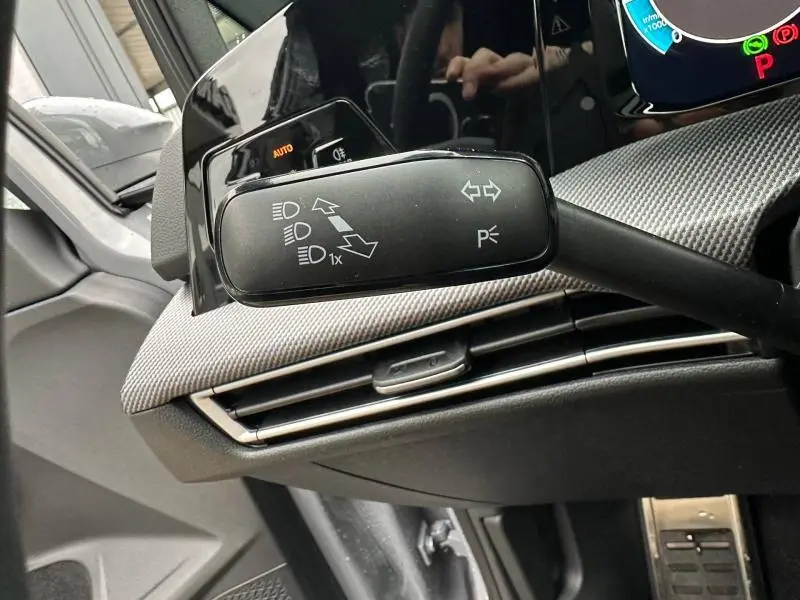 Gros plan sur la commande de clignotants noire avec symboles blancs, tableau de bord gris texturé d'une Volkswagen Golf gris Urano.