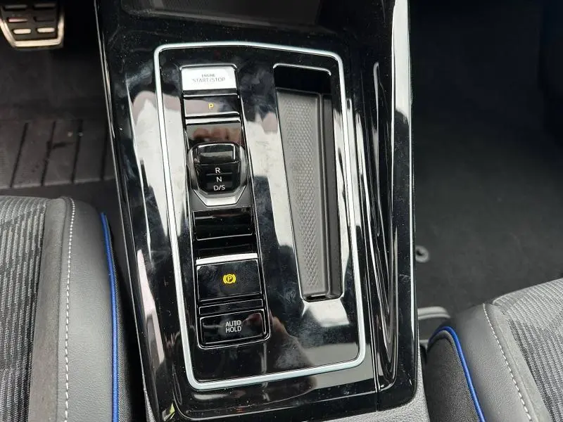 Gros plan sur la console centrale noire brillante de la Volkswagen Golf 2.0 TDI 150ch R-Line avec sélecteur de boîte auto et bouton start/stop.