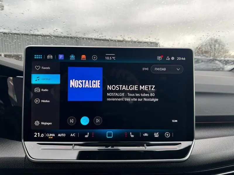 Vue intérieure centrée sur l'écran tactile multimédia du Volkswagen Golf gris, avec affichage radio Nostalgie.