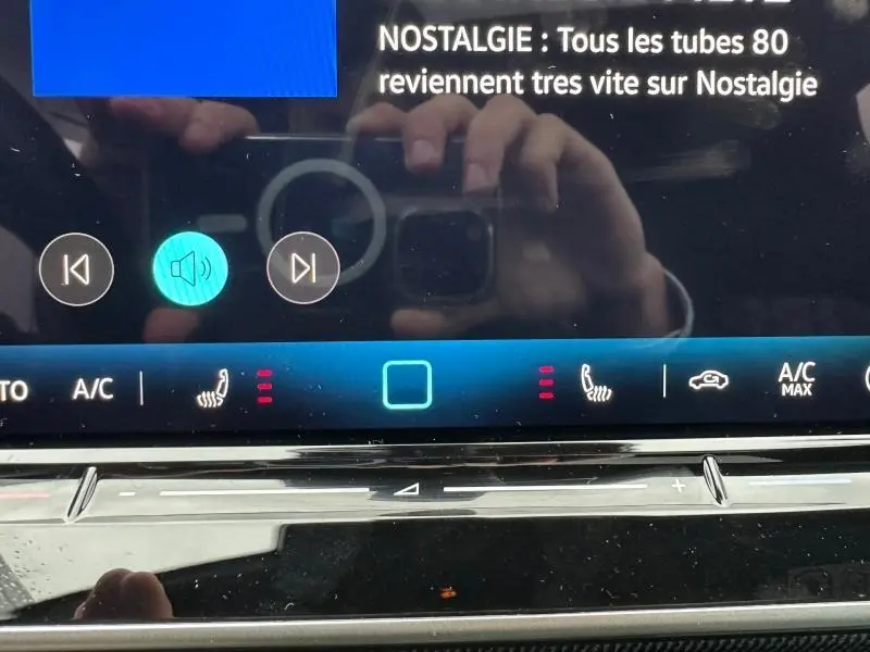 Gros plan sur l'écran tactile de la Volkswagen Golf gris 2026, affichant la climatisation et la radio Nostalgie.