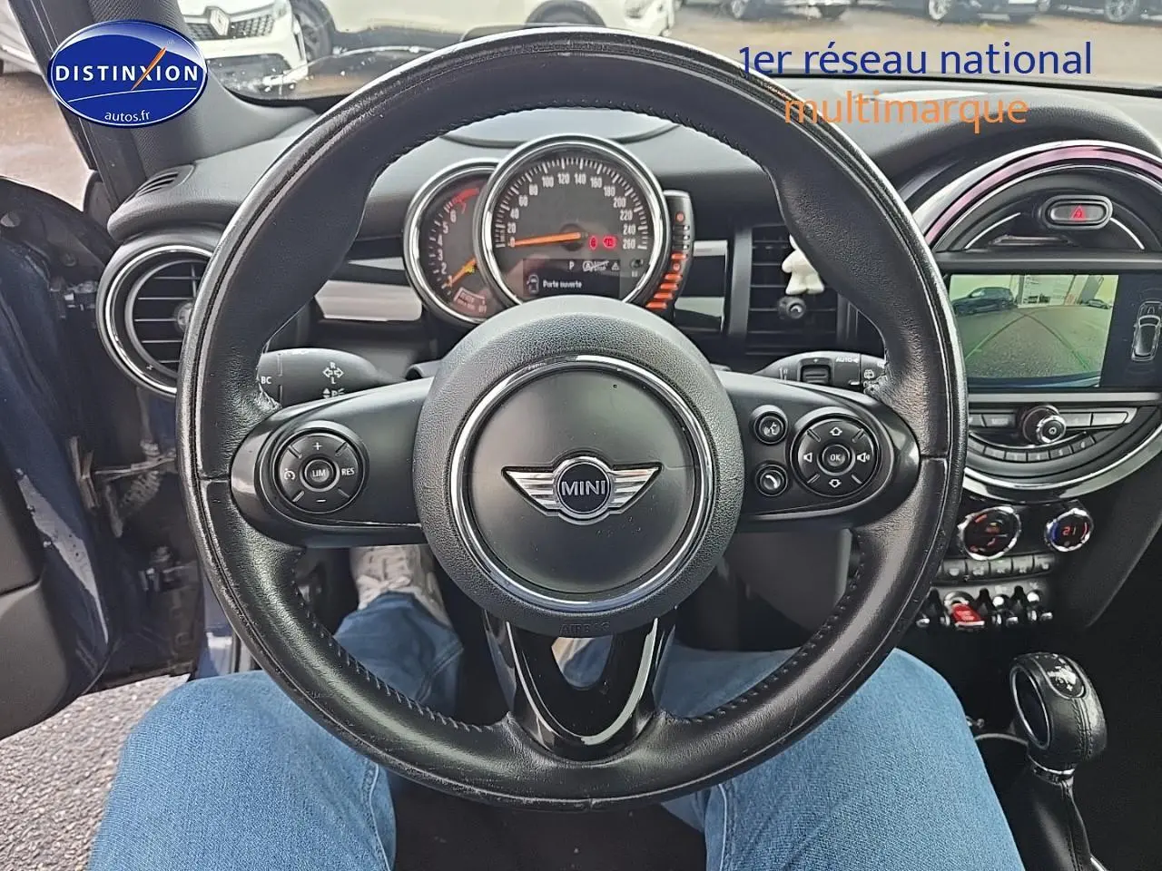 Vue centrée sur le volant cuir multifonction d'une MINI Cooper S bleu nuit, avec tableau de bord et écran multimédia visibles.