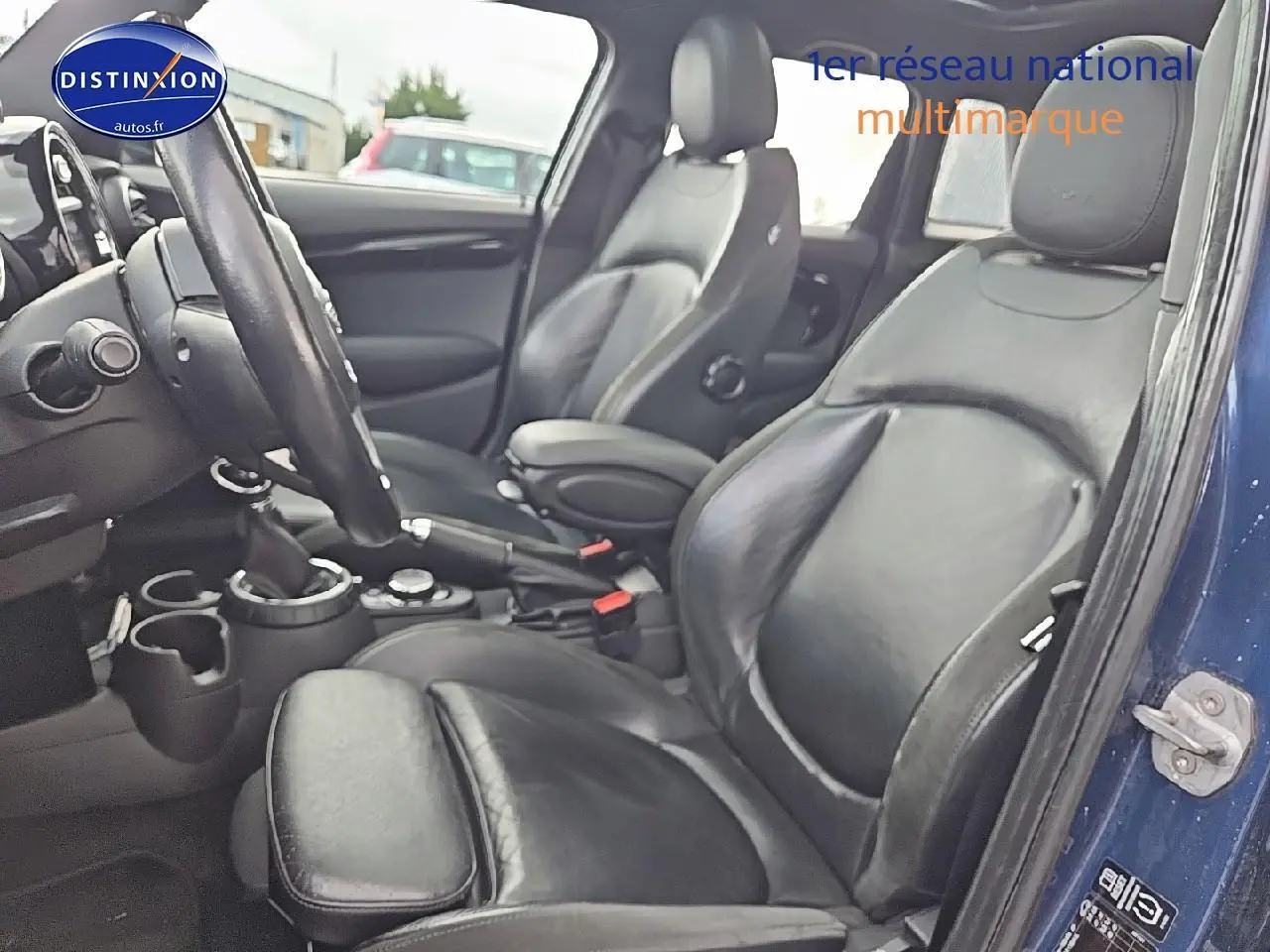 Vue intérieure côté conducteur de la MINI Cooper S 2015 avec sièges sport en cuir noir et portière bleu nuit ouverte.