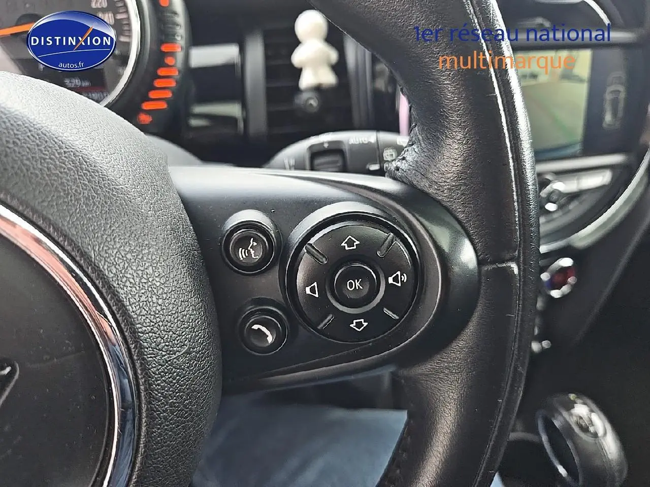 Gros plan sur les commandes au volant cuir noir d'une MINI Cooper S 2015, avec tableau de bord et écran central en arrière-plan.