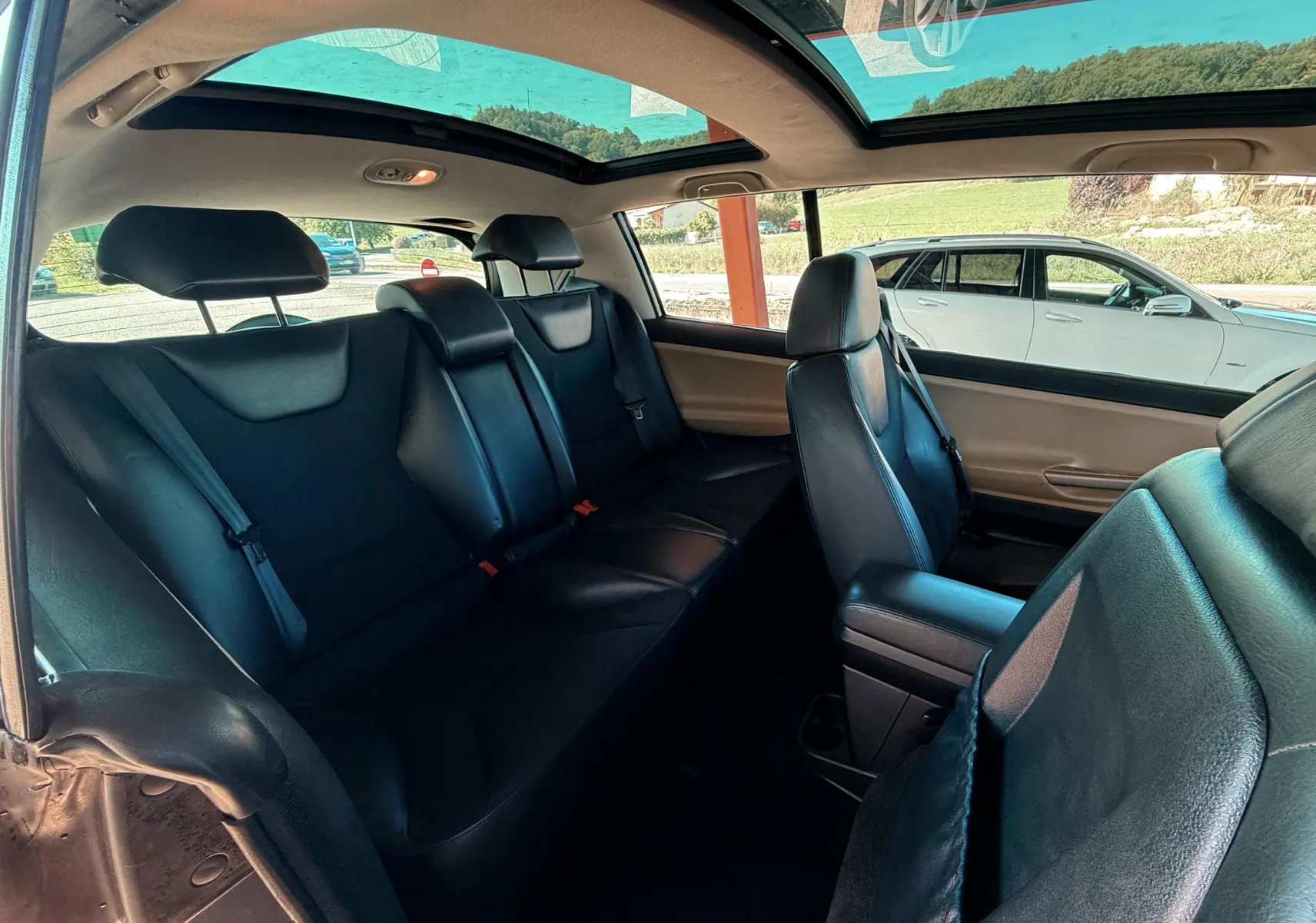 Intérieur arrière de la Renault Avantime gris, avec sièges en cuir noir et toit panoramique visible.