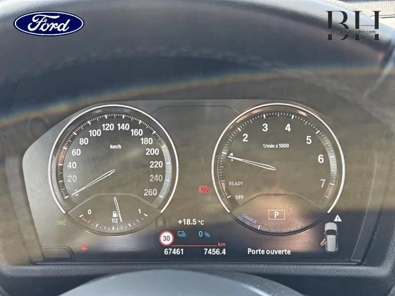 Vue rapprochée du tableau de bord de la BMW X1 xDrive25eA 220ch en noir Saphirschwarz, affichant les compteurs et alertes.