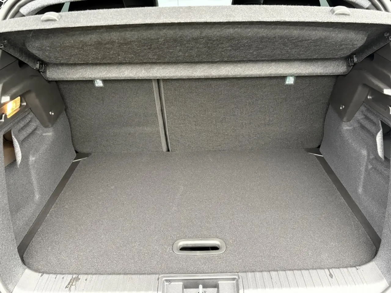 Coffre ouvert du Renault Captur 2025 hybride, vue intérieure montrant le plancher plat et la moquette grise.