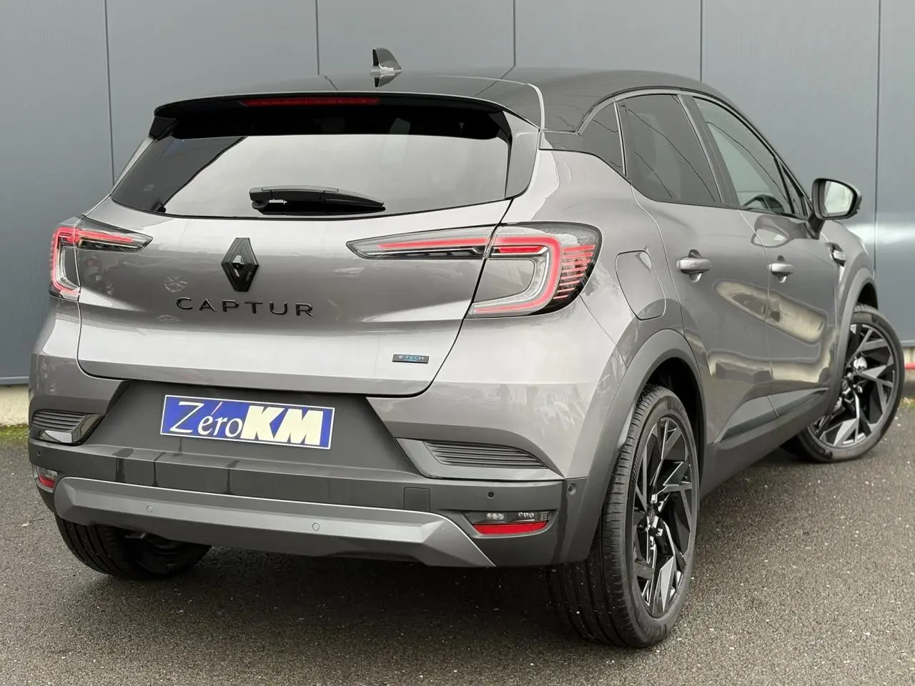 Vue 3/4 arrière droite d'un Renault Captur gris Cassiopée avec toit noir et jantes noires distinctives.