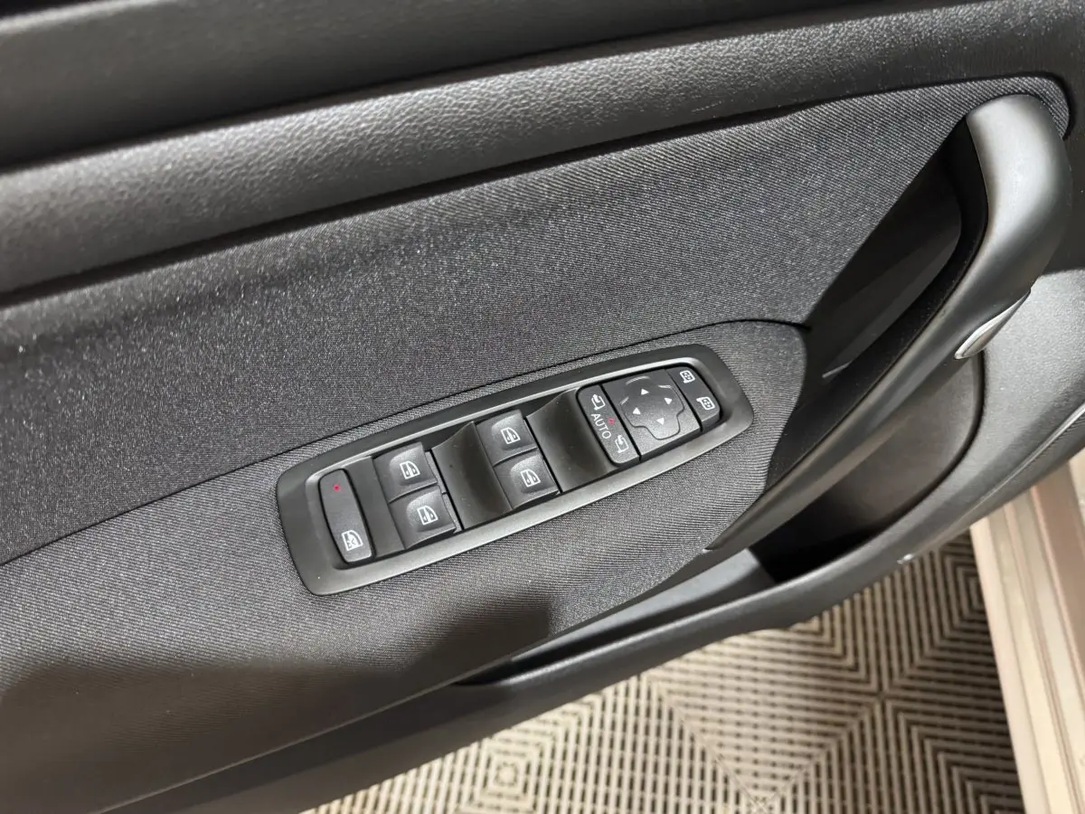 Vue rapprochée de la porte côté conducteur de la Renault Mégane Business gris clair avec commandes électriques des vitres et rétroviseurs.