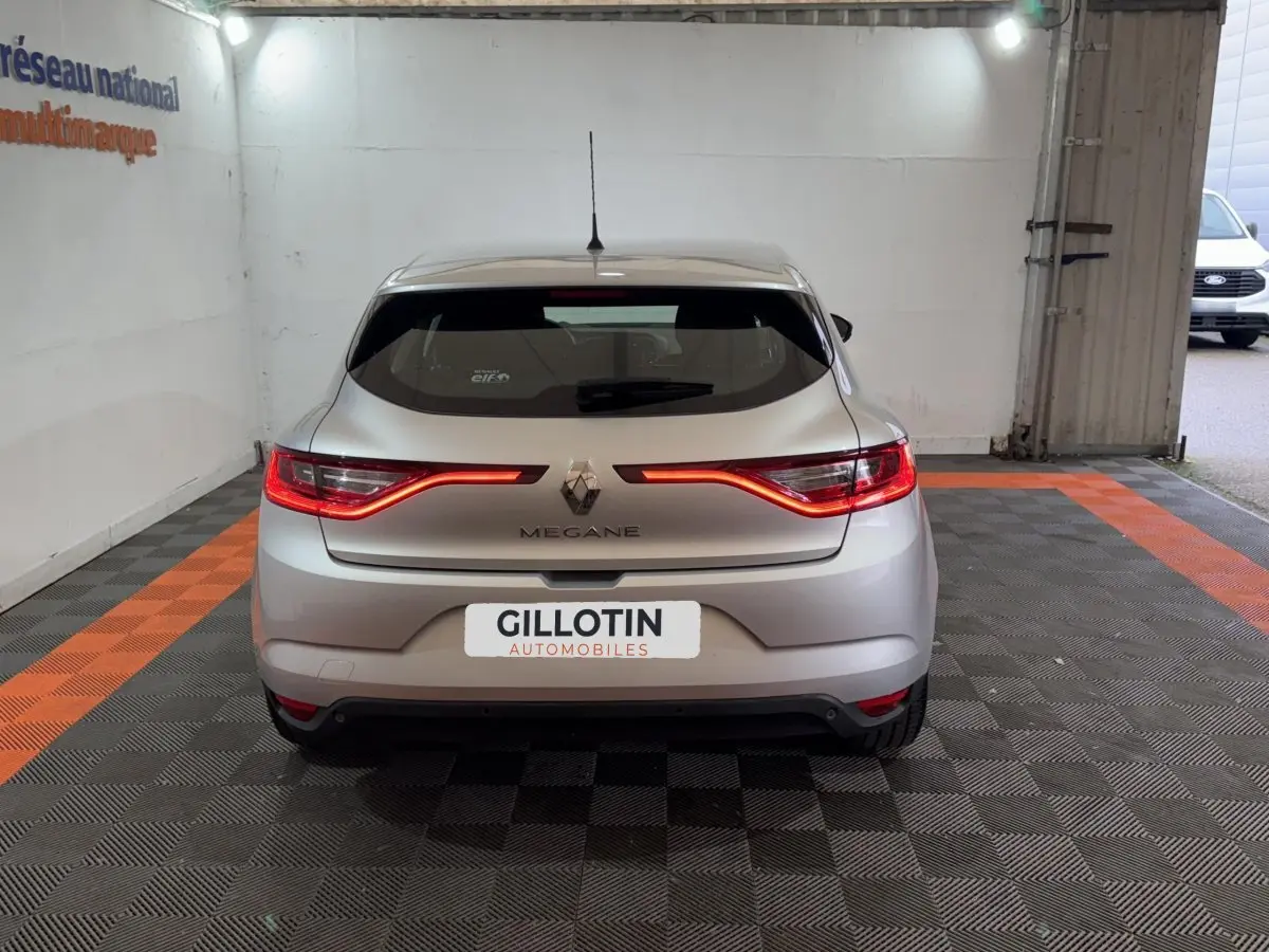 Vue arrière d'une Renault Mégane gris clair avec feux arrière LED allumés dans un garage.