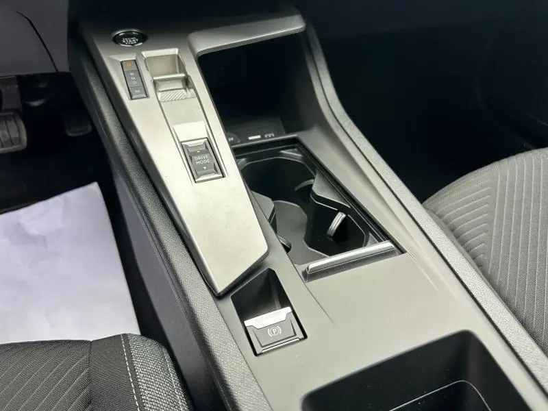 Gros plan sur la console centrale noire de la Peugeot 308 2024, mettant en valeur les commandes de boîte auto et porte-gobelets.