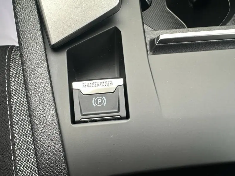 Gros plan sur le bouton de frein à main électronique dans l'habitacle noir du Peugeot 308 2024.