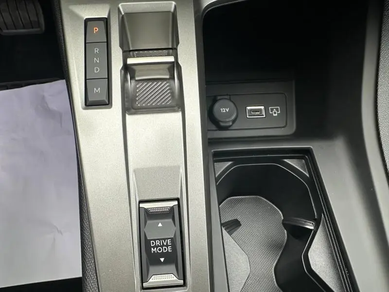 Vue rapprochée de la console centrale de la Peugeot 308 2024 avec boîte auto, boutons Drive Mode et prise 12V visible.