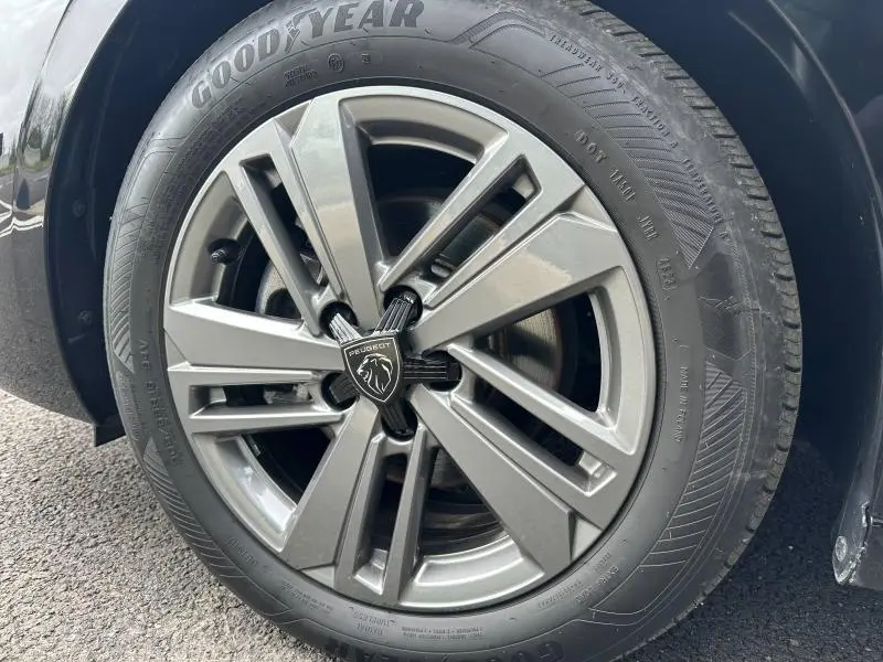 Gros plan sur la jante avant droite gris métallisé de la Peugeot 308 2024 Noir Perla Nera avec logo lion central.