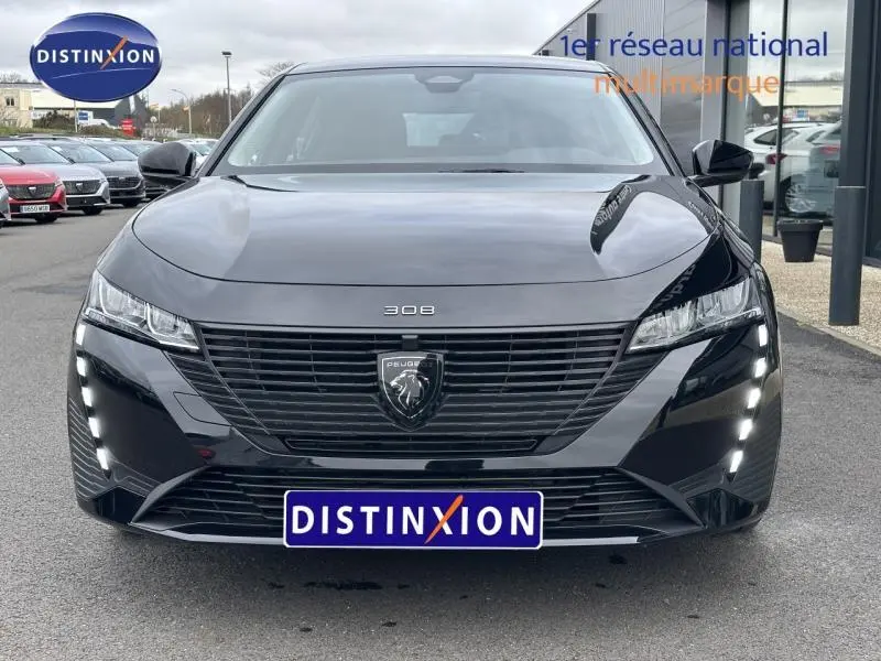 Vue frontale d'une Peugeot 308 2024 noire Perla Nera avec calandre noire et feux LED verticaux allumés.