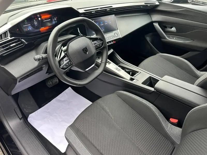Vue intérieure côté conducteur de la Peugeot 308 2024, tableau de bord numérique et volant compact noir.
