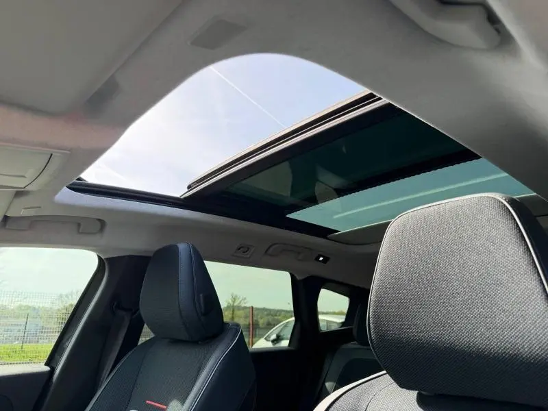 Vue intérieure du toit ouvrant panoramique et des sièges avant en tissu bleu avec surpiqûres blanches du Citroën C5 Aircross gris Platinium.