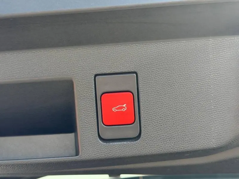 Bouton rouge d'ouverture électrique du coffre sur panneau intérieur gris du Citroën C5 Aircross Hybride 2026.