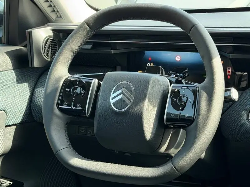 Vue rapprochée du volant multifonction noir du Citroën C5 Aircross 2026 avec tableau de bord numérique en arrière-plan.