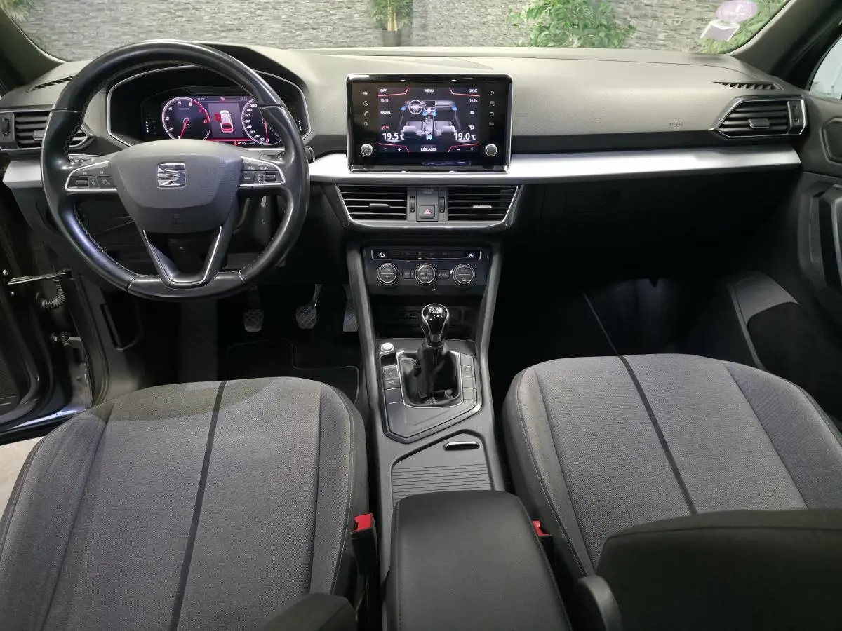 Vue intérieure avant du SEAT Tarraco gris, montrant le tableau de bord, volant cuir multifonction et levier de vitesse manuel.