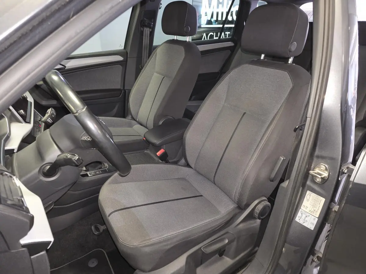Vue intérieure côté conducteur du SEAT Tarraco gris, mettant en valeur les sièges tissu gris et le volant cuir multifonction.