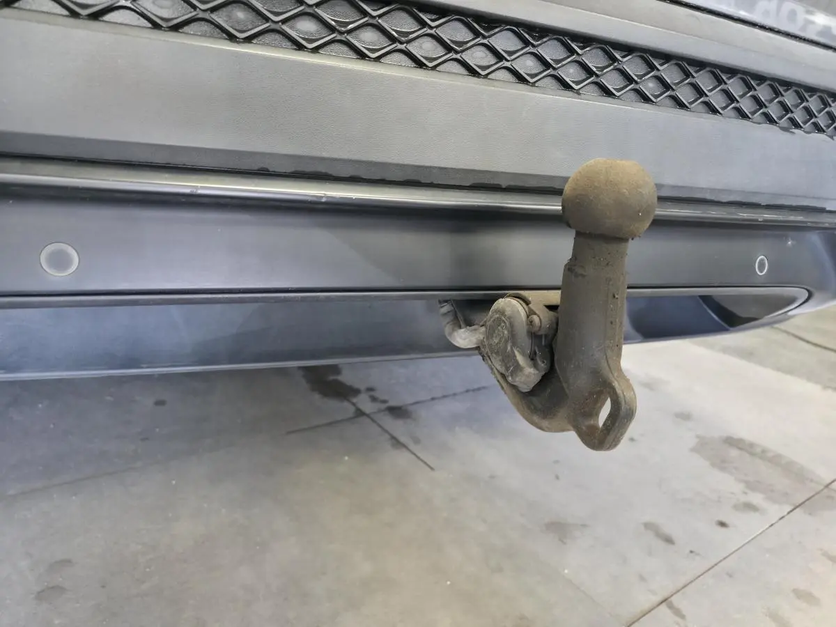 Gros plan sur le crochet d'attelage escamotable arrière du SEAT Tarraco gris, avec capteurs de stationnement visibles.