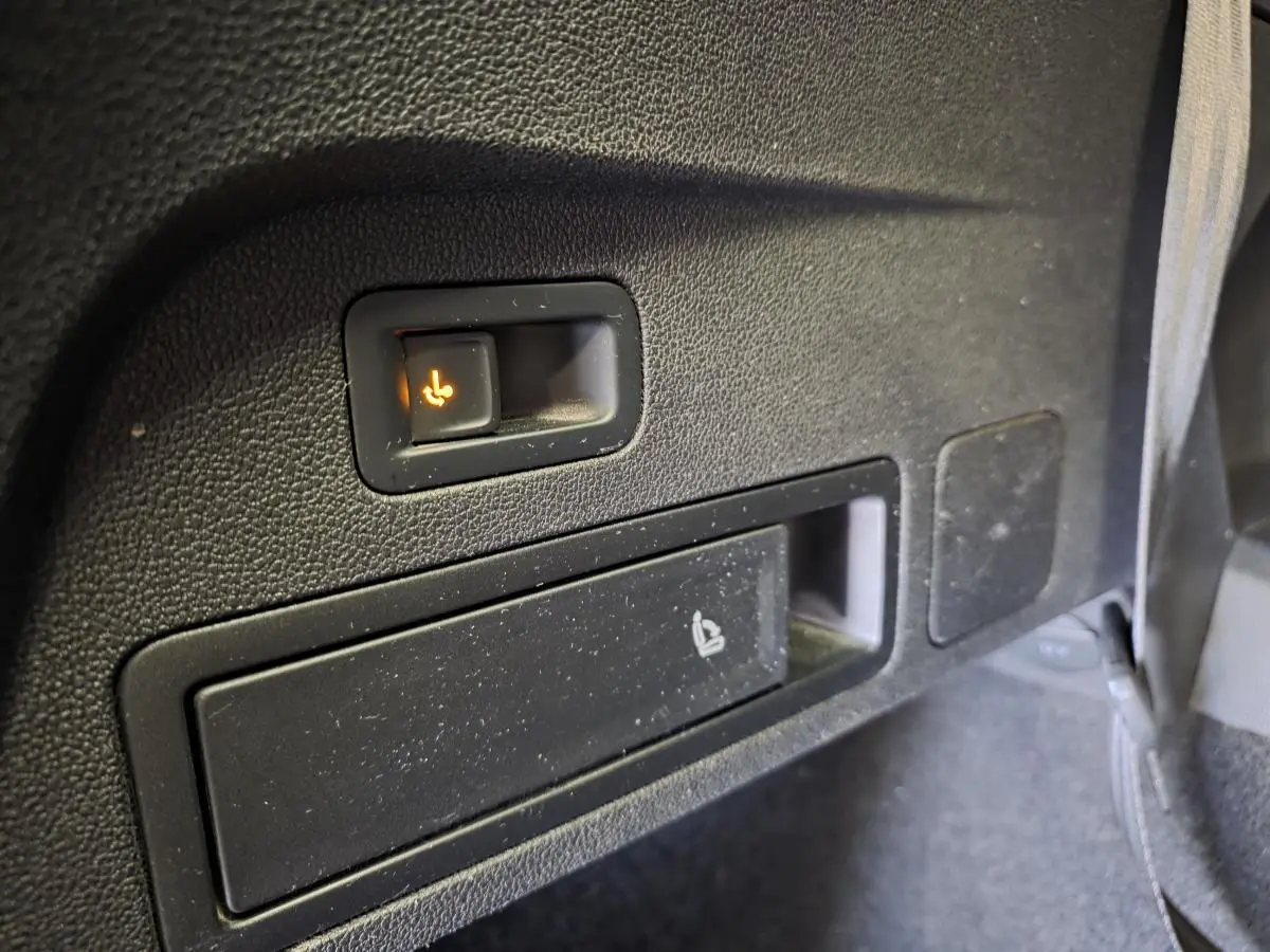 Détail du bouton de rabattement électrique des sièges arrière sur le côté droit d’un SEAT Tarraco gris.