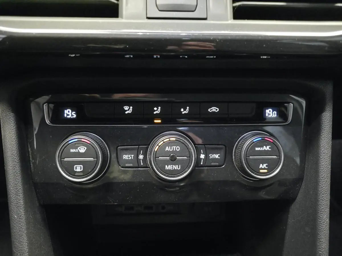 Gros plan sur la console centrale noire du SEAT Tarraco 2020, montrant les commandes de climatisation tri-zone digitales.