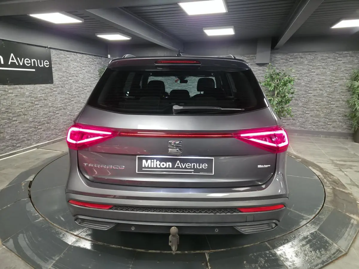 Vue arrière d'un SEAT Tarraco gris avec feux LED allumés et crochet d'attelage escamotable visible.
