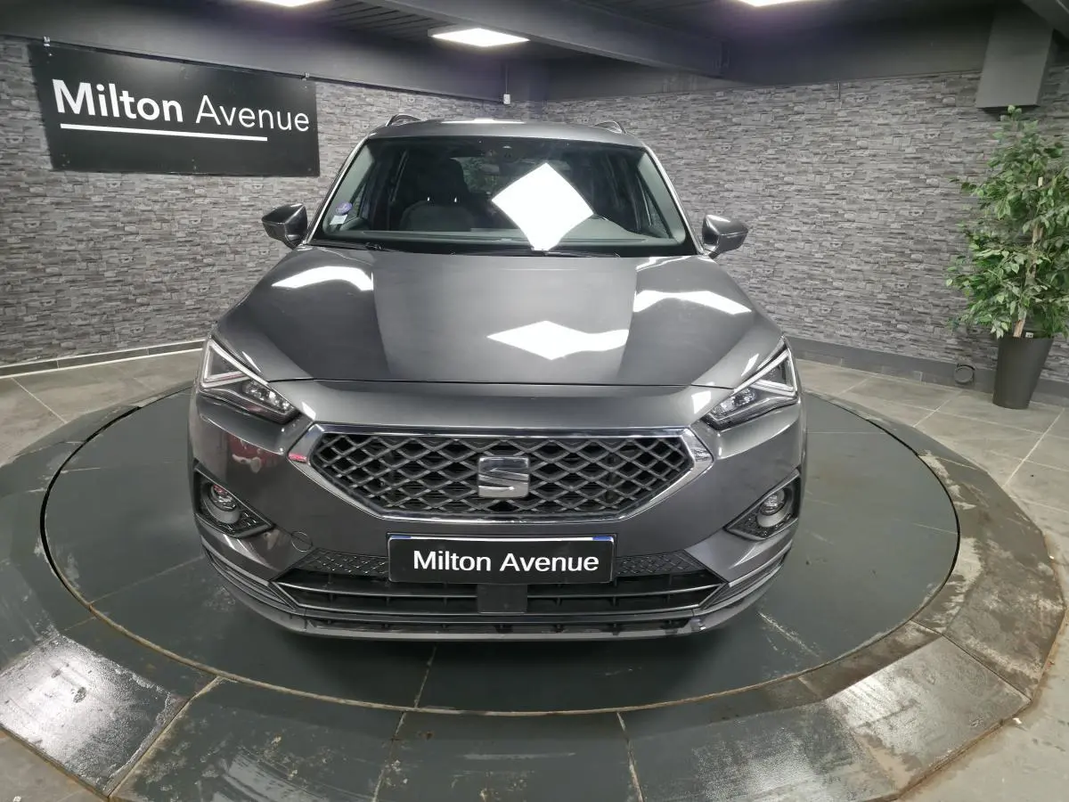 Vue avant d'un SEAT Tarraco gris Urano avec calandre hexagonale et phares Full LED dans un showroom.
