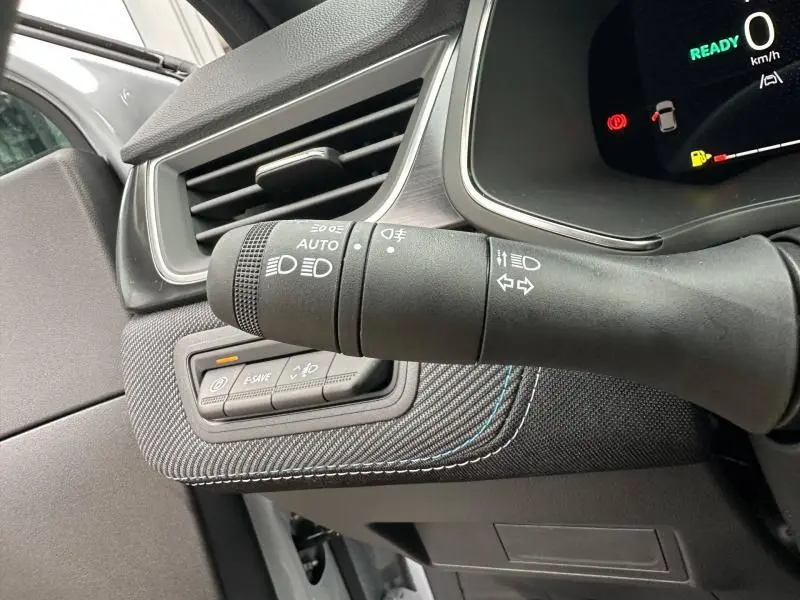 Gros plan intérieur sur la commande des phares et clignotants du Renault Captur 2026, détails en tissu gris avec surpiqûres bleues.
