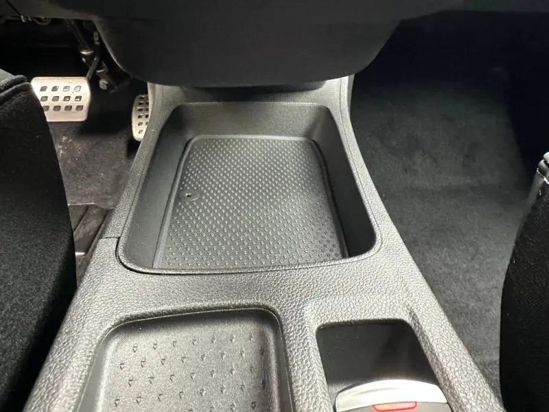 Gros plan sur la console centrale intérieure du Renault Captur 2026 hybride, montrant un rangement texturé et les pédales en aluminium.