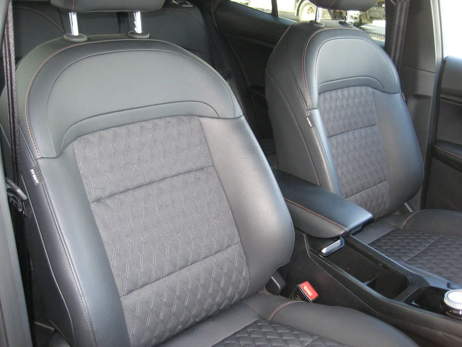 Gros plan sur les sièges avant en cuir noir et tissu gris avec surpiqûres orange dans l’habitacle du MG3 1.5 Hybrid Luxury 2025.