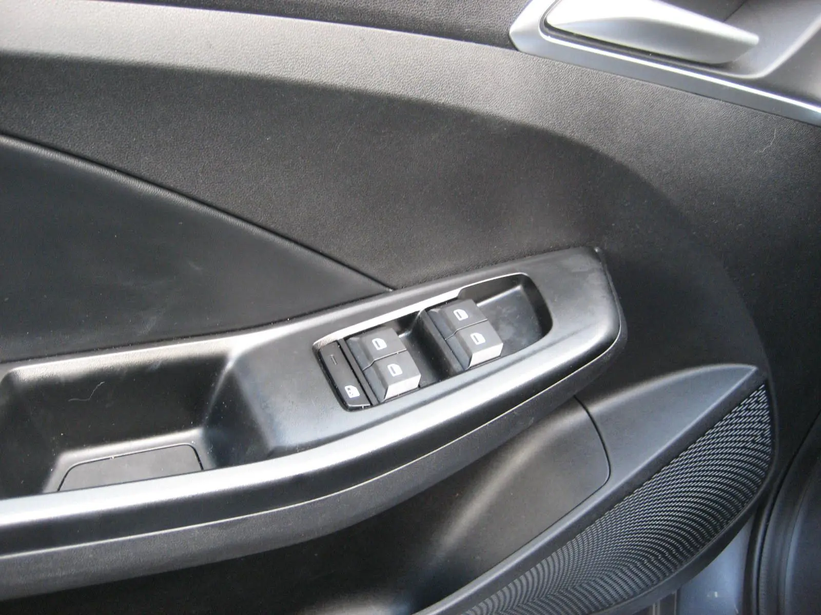 Gros plan sur la commande des vitres électriques côté gauche d’une MG3 1.5 Hybrid gris, intérieur noir.