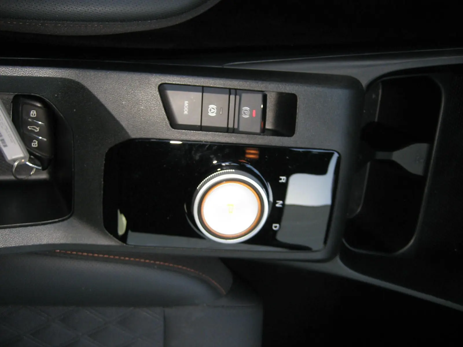 Gros plan sur la console centrale noire du MG3 1.5 Hybrid 2025 avec molette de boîte auto et boutons de frein à main électronique.