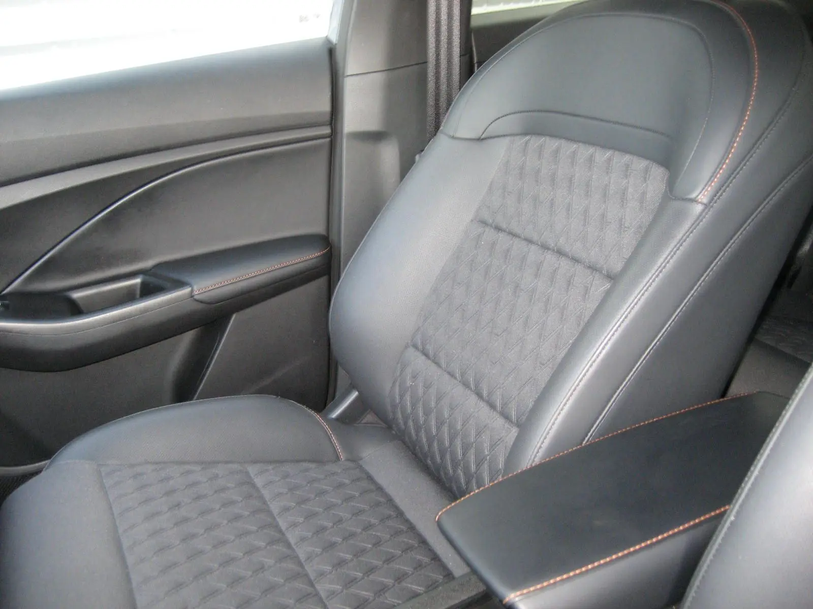 Gros plan sur le siège avant droit en cuir noir avec surpiqûres orange du MG3 1.5 Hybrid Luxury gris 2025.