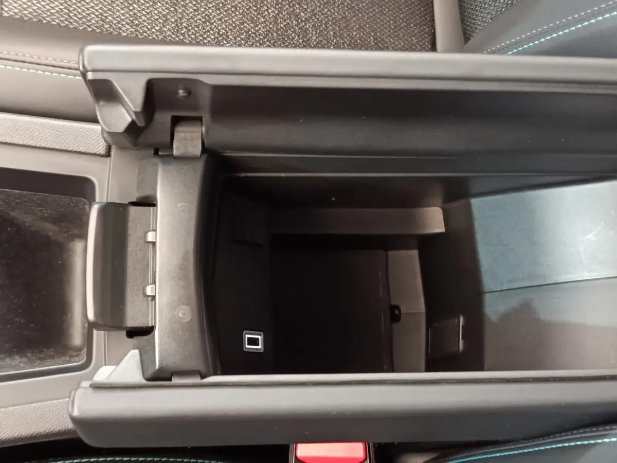 Vue plongeante sur le rangement central ouvert de la Peugeot 308, intérieur noir avec port USB visible.