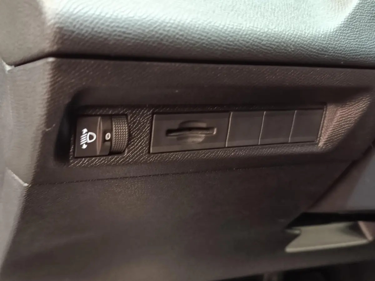 Vue rapprochée du tableau de bord noir de la Peugeot 308 2023, avec commande de réglage des phares.