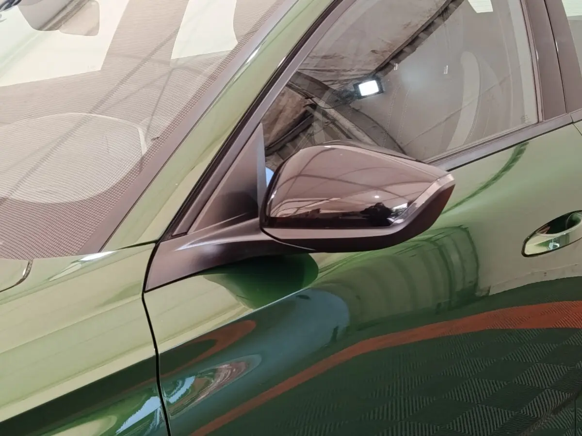 Gros plan sur le rétroviseur droit noir brillant et la portière verte d'une Peugeot 308 2023 vue côté droit.