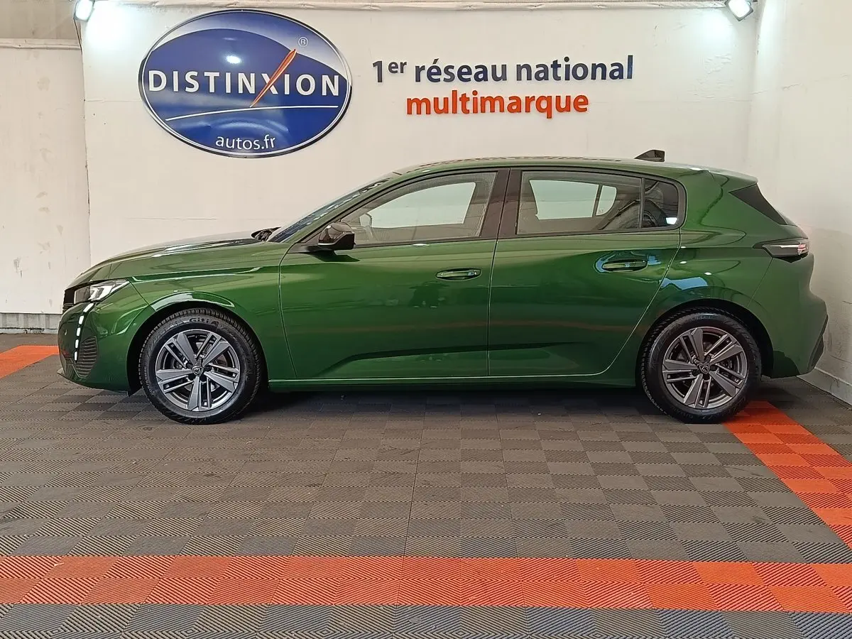 Peugeot 308 vert vue de profil côté gauche, avec jantes alliage et feux LED distinctifs, en intérieur showroom.