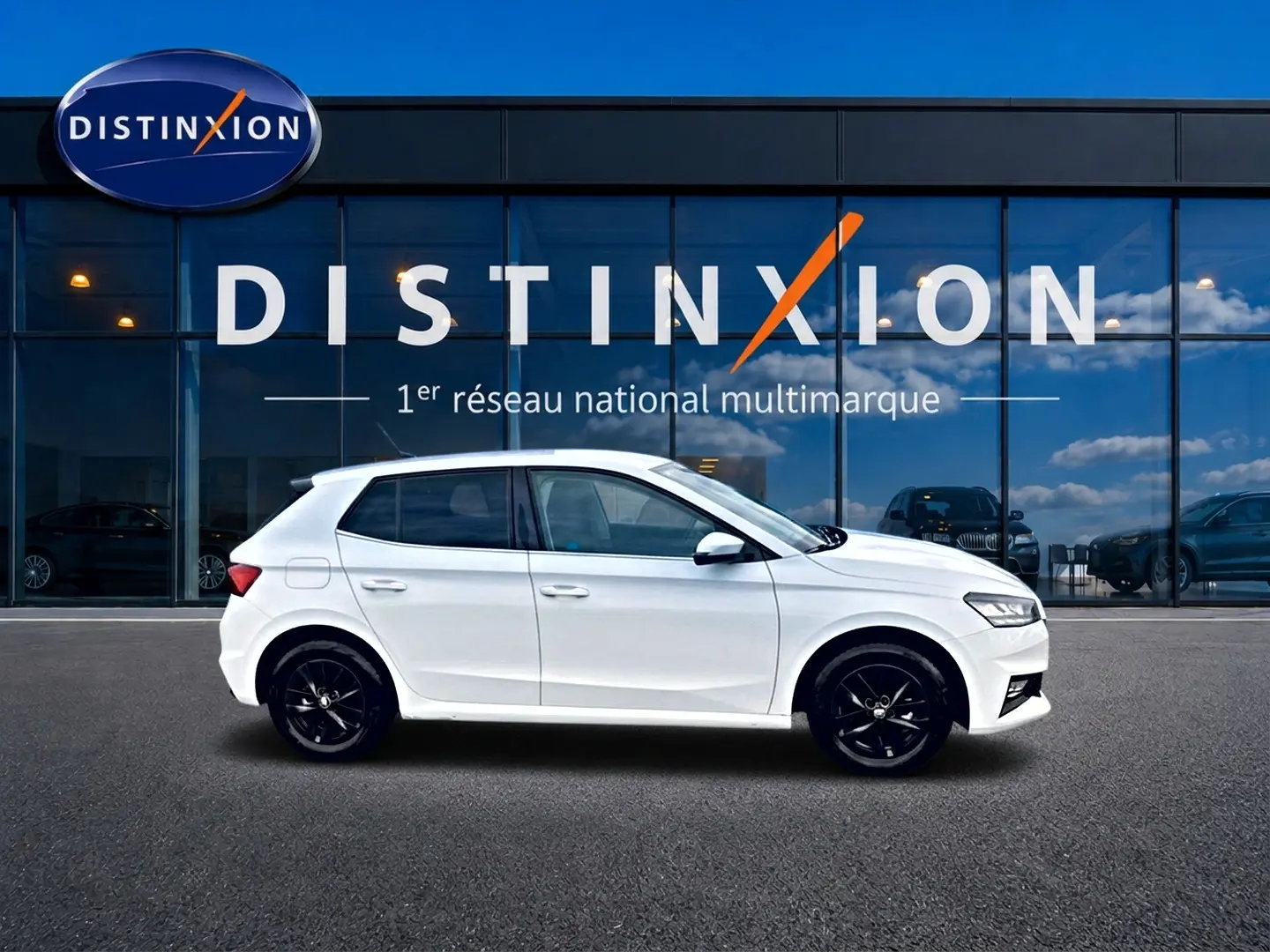 Vue de profil côté gauche d'une Skoda Fabia blanche 2025 avec jantes noires devant une vitrine Distinxion.