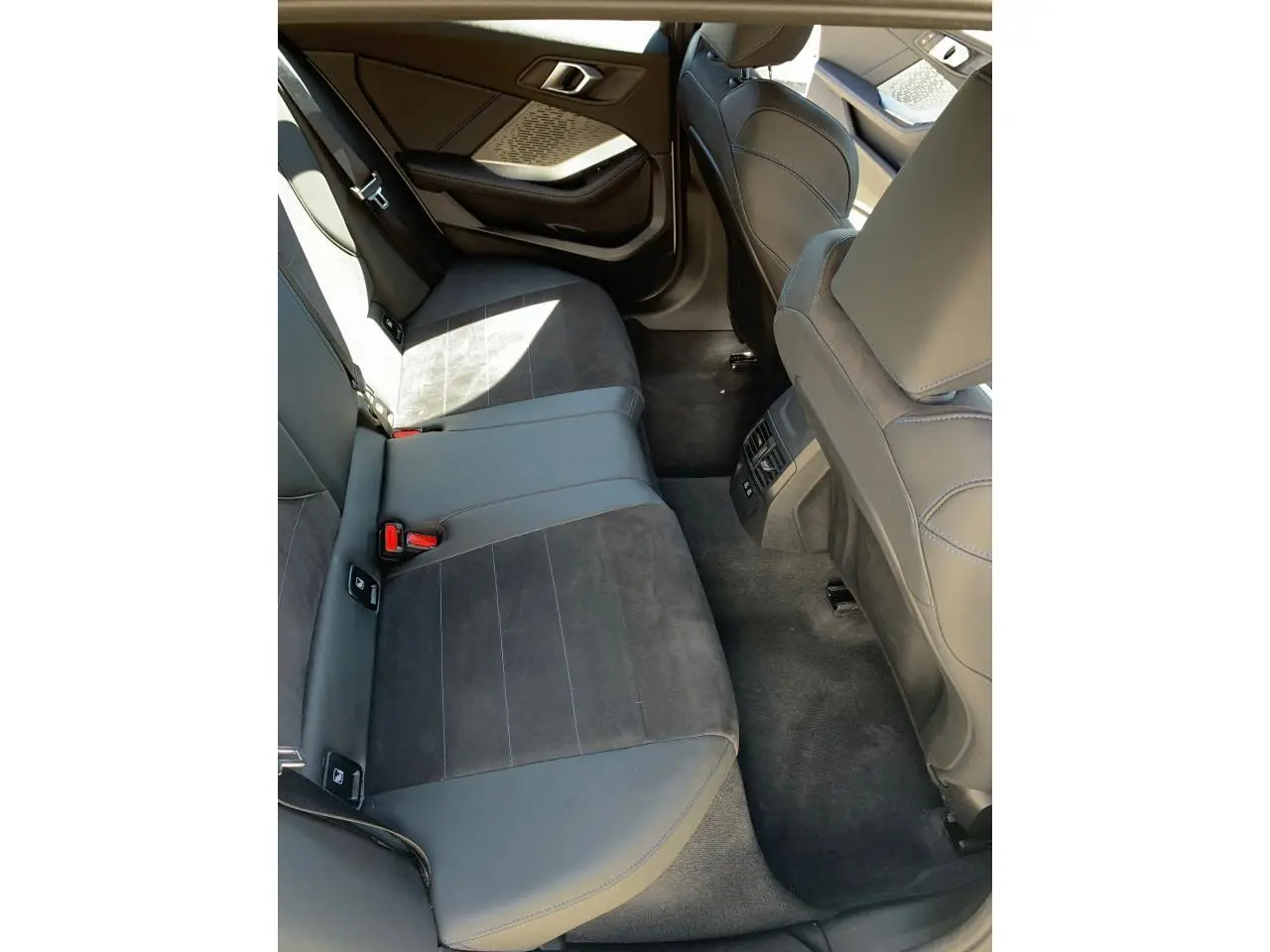 Vue intérieure côté gauche des sièges arrière en Alcantara noir et cuir avec surpiqûres bleues d'une BMW Série 1 118D M Sport 2025.